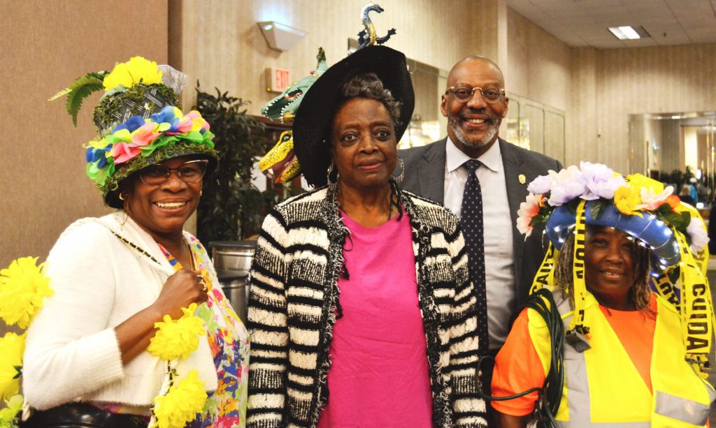 During the community celebration, the three winners of the Crazy Hat Competition pose for a photo with Solicitor Byron Gipson, showing off their colorful and creative hats.